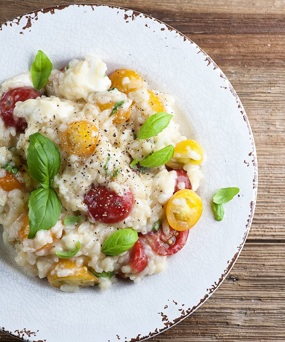 Tomato basil mozzarella risotto on a plate.