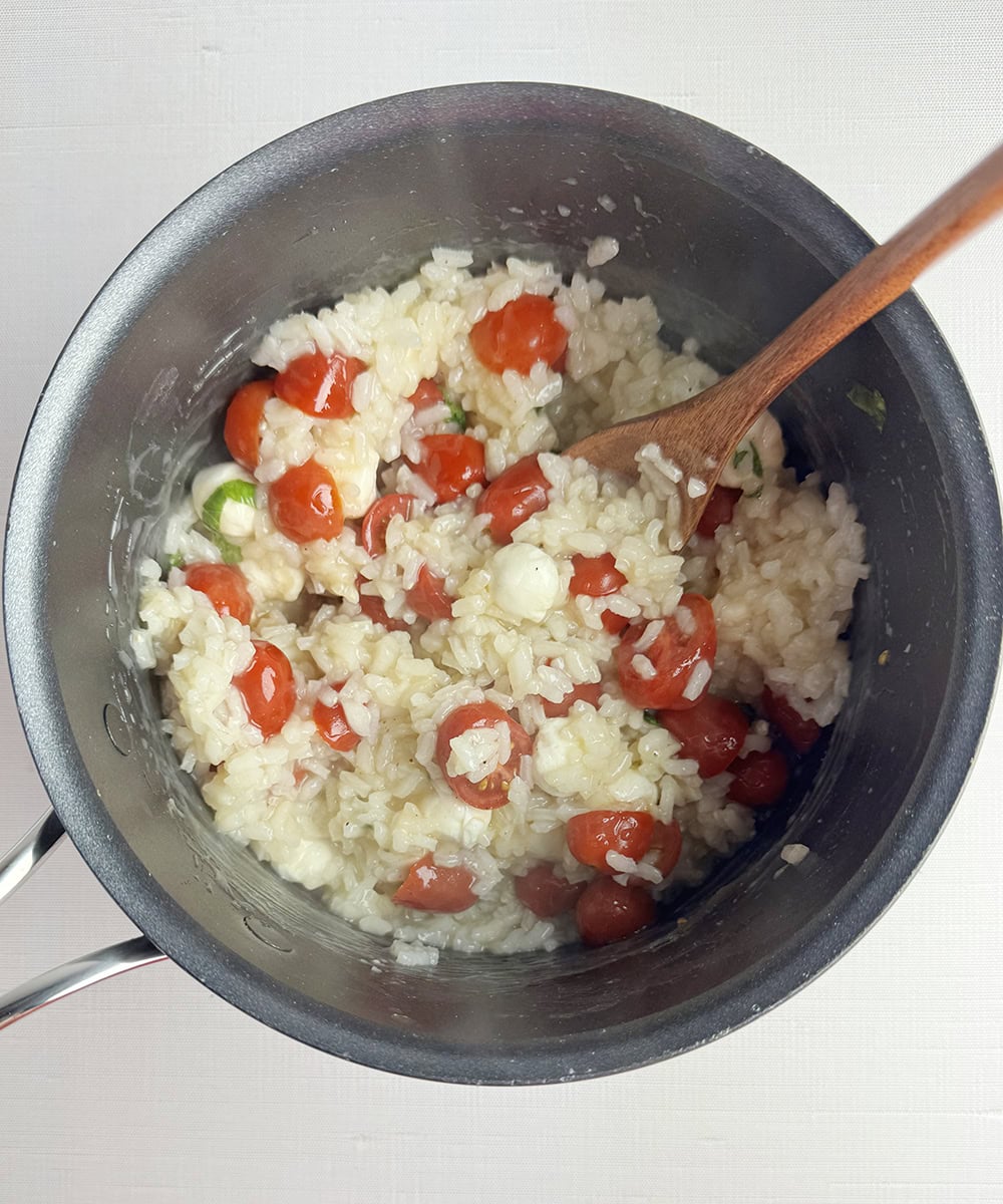 Tomato risotto in a pot with a spoon.