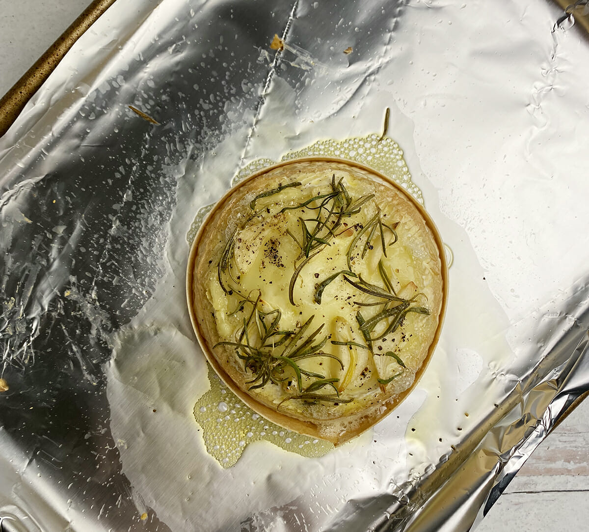 Baked camembert and rosemary on cookie sheet.