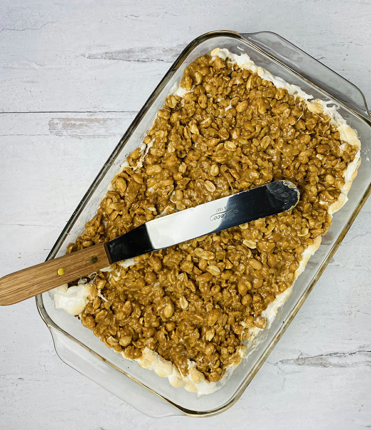 Spreading topping on Payday bars with an offset spatula.
