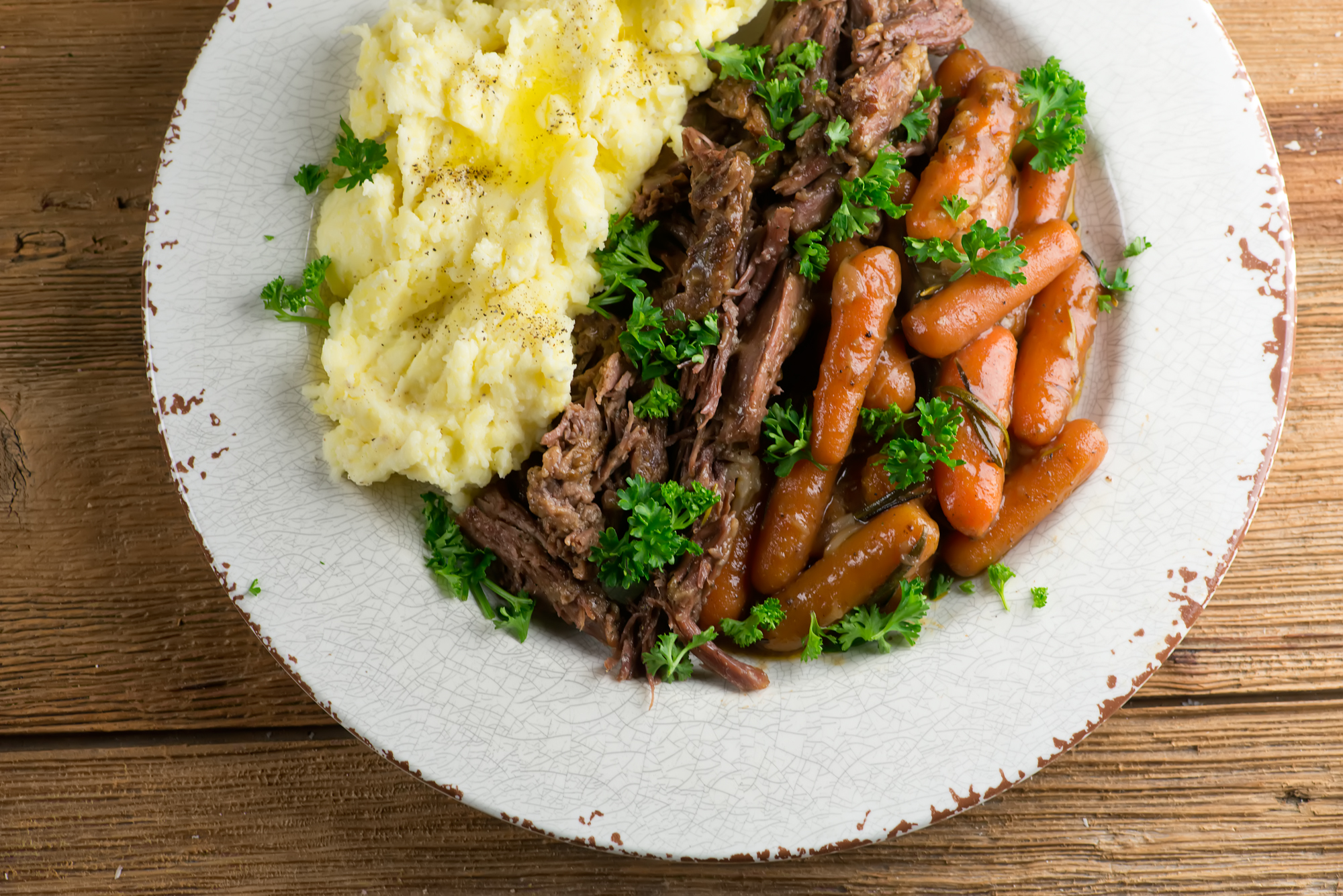 Shredded pot roast on a plate with mashed potatoes.
