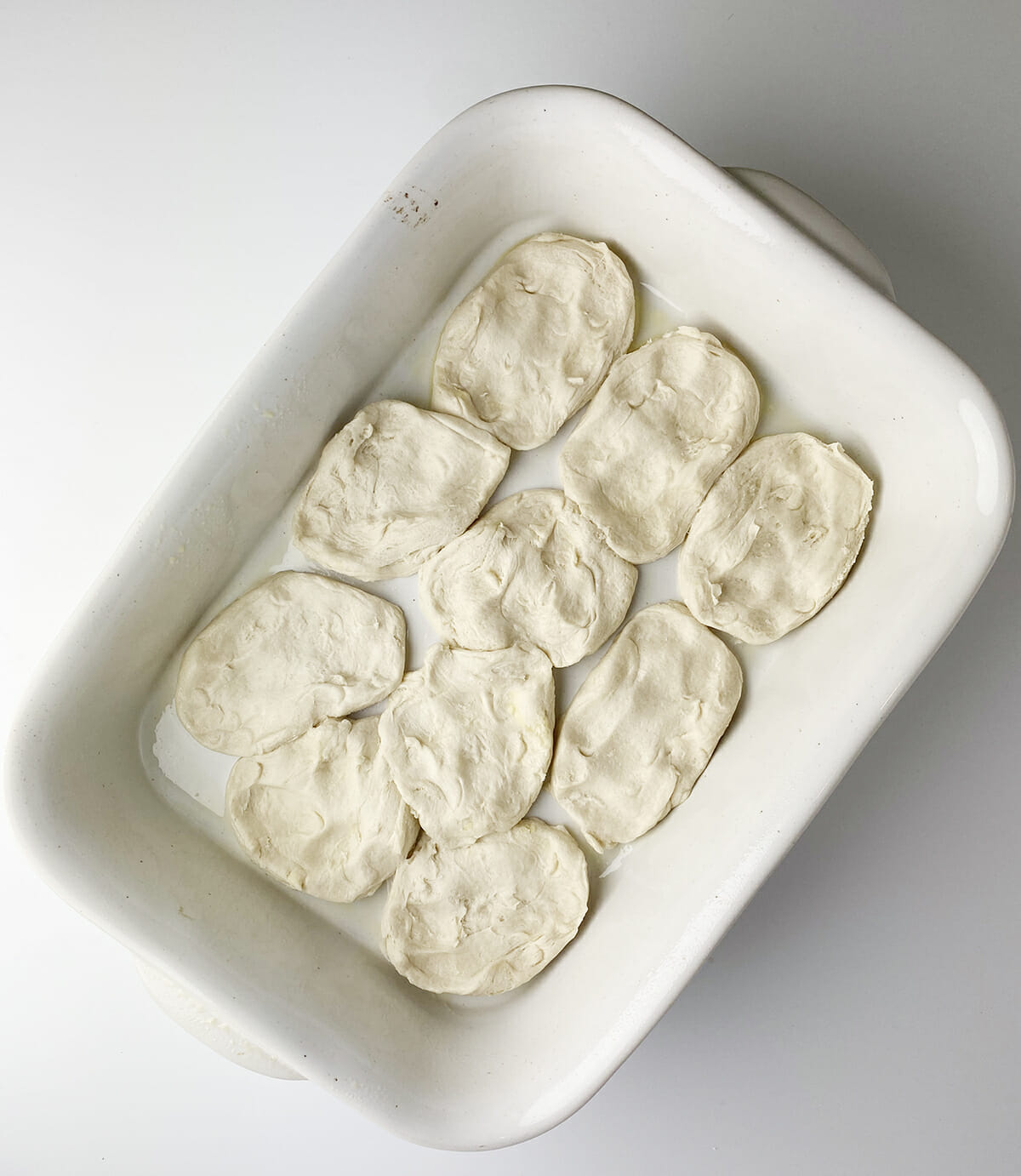 Refrigerator biscuits flattened into a casserole dish.