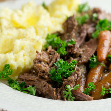 Shredded pot roast on a plate with mashed potatoes.