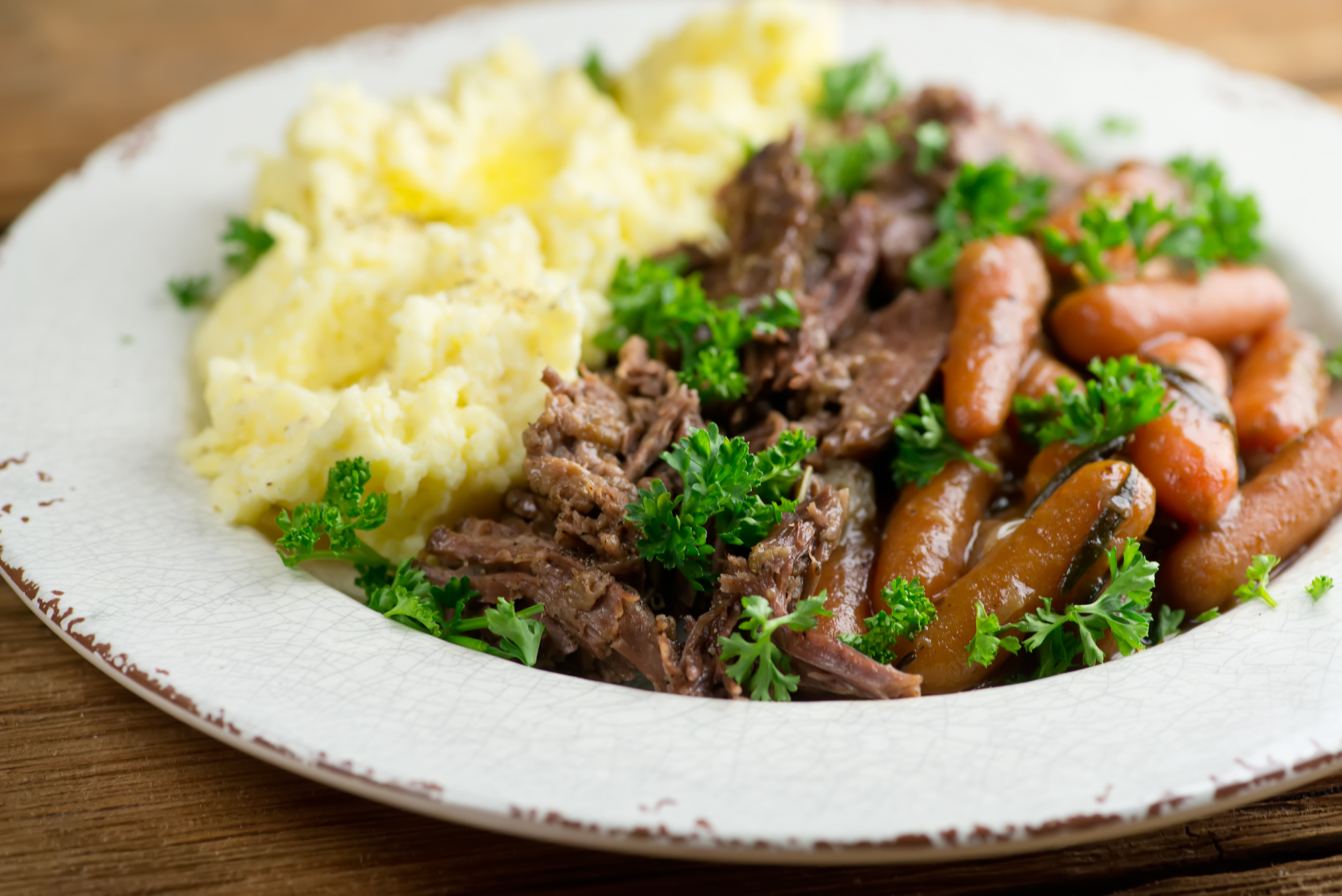 Shredded pot roast on a plate with mashed potatoes.