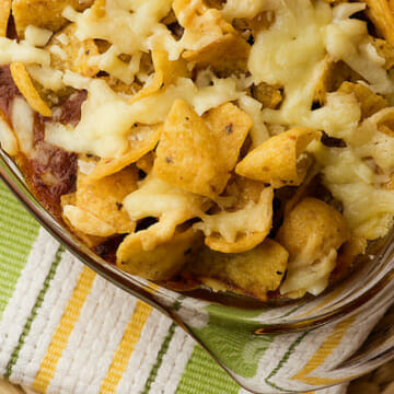 Frito chili pie in a casserole sitting on a dishcloth.