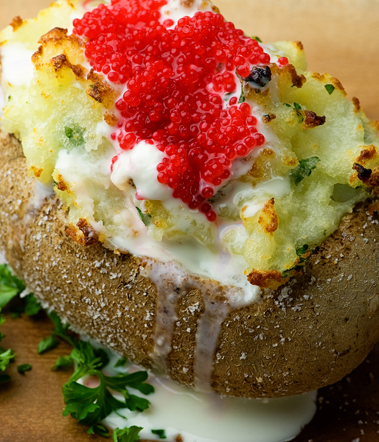 A baked potato with sour cream and caviar ready for serving.