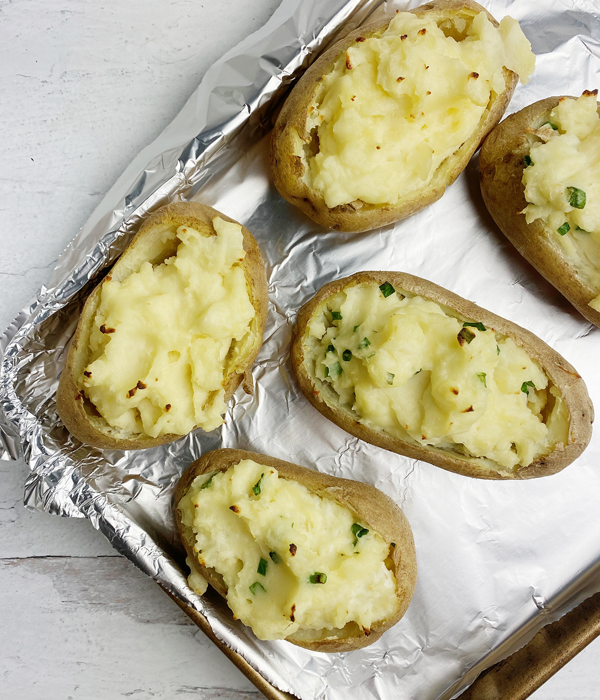 Baked and stuffed potatoes on a baking tray.