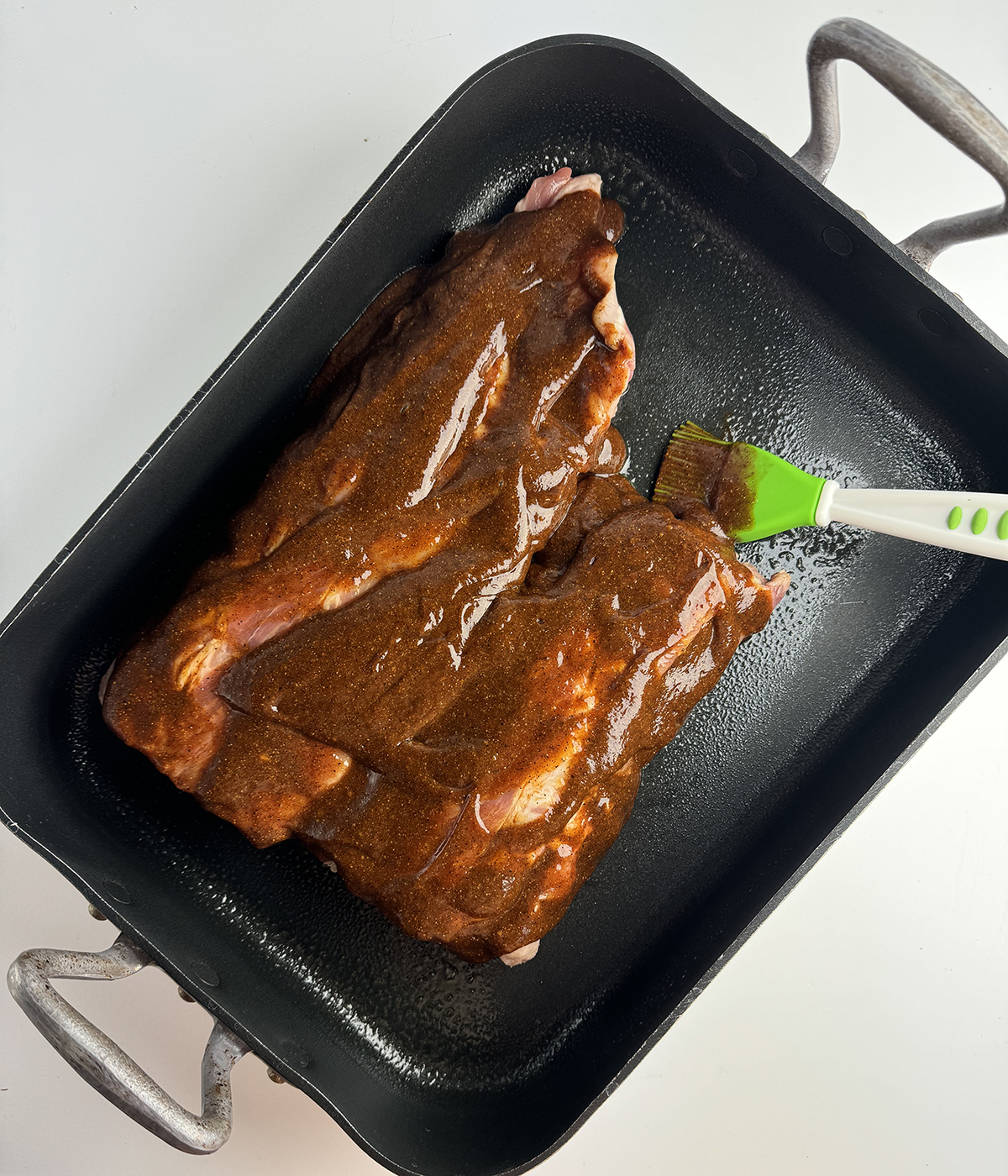 Coca Cola Ribs being basted in a roasting pan.