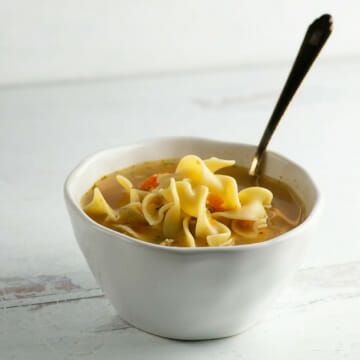 Chicken noodle soup in a bowl with a spoon.