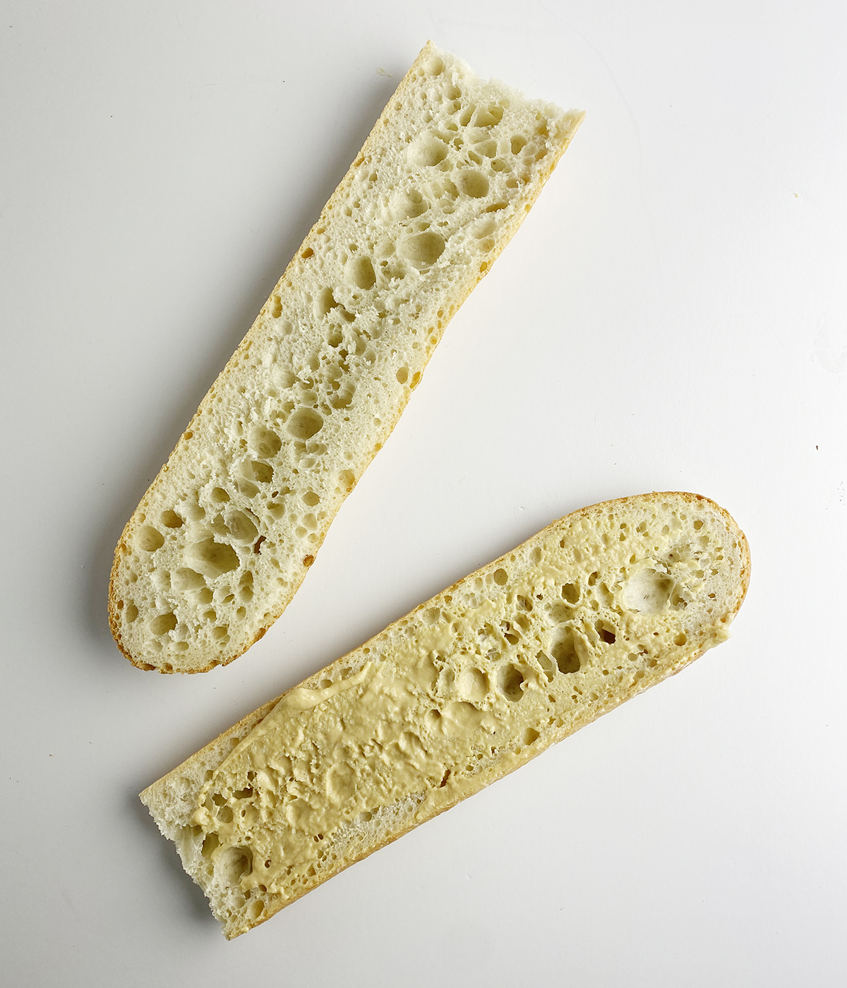 French bread cut in half and spread with mustard.