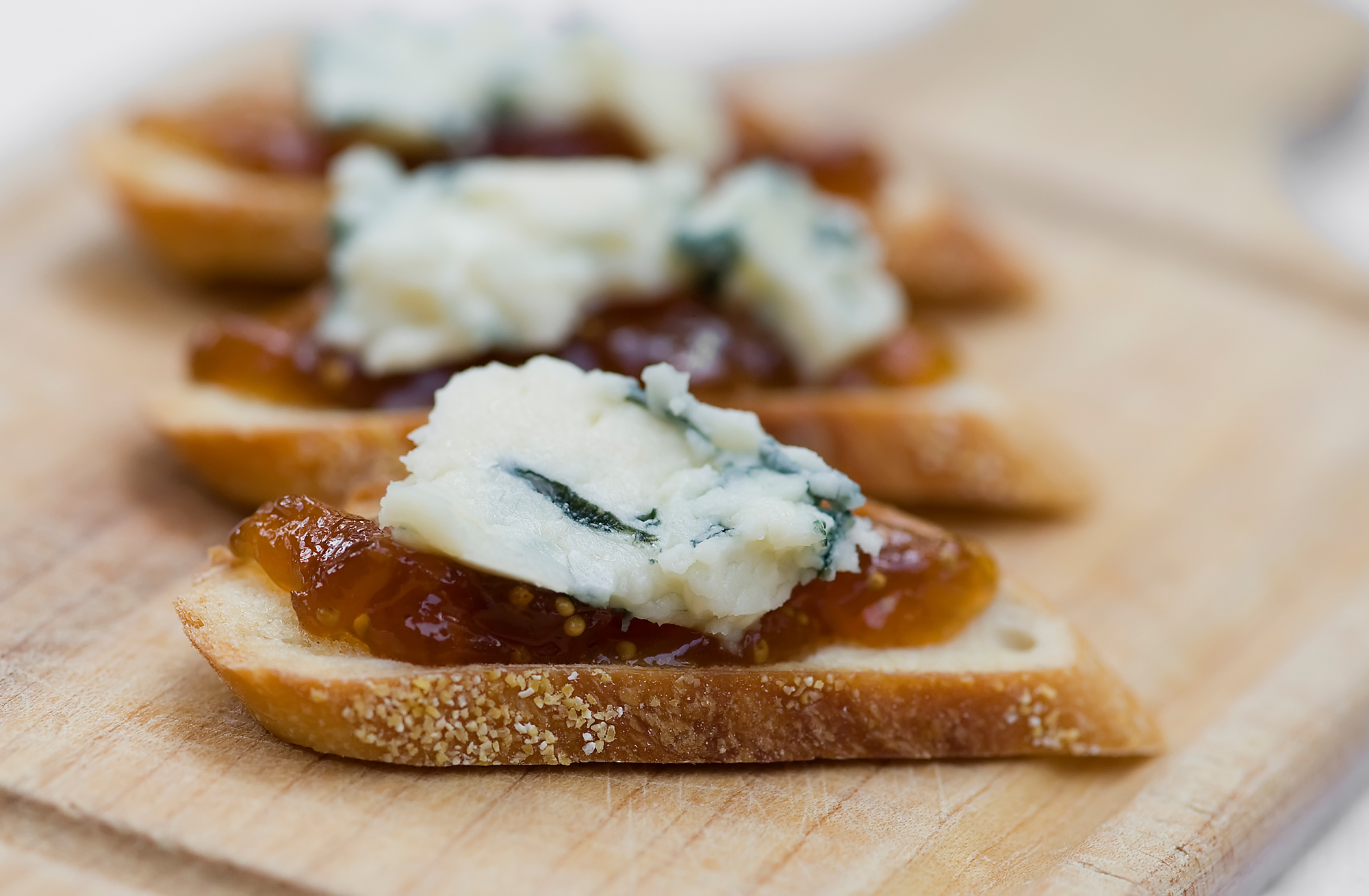 Blue cheese and fig jam crostini ona wooden board.