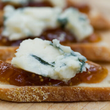 Blue cheese and fig jam crostini on a wooden noard.