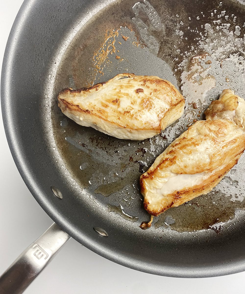Chicken breasts browning in a skillet.