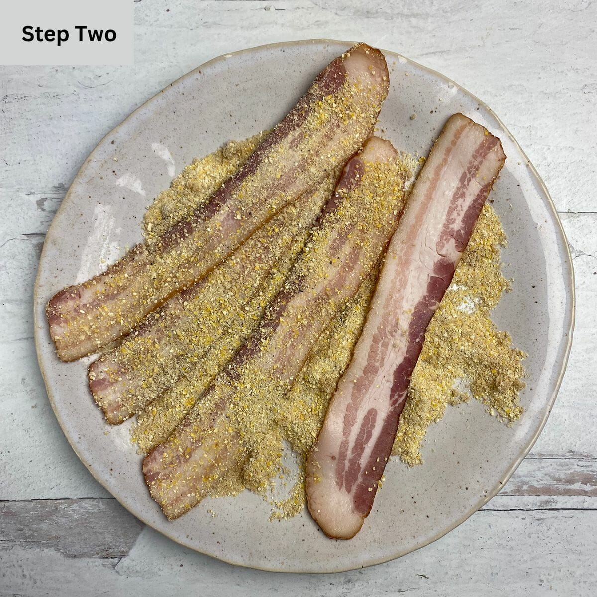 Bacon being dredged in a brown sugar and cornmeal mixture in a pie plate.