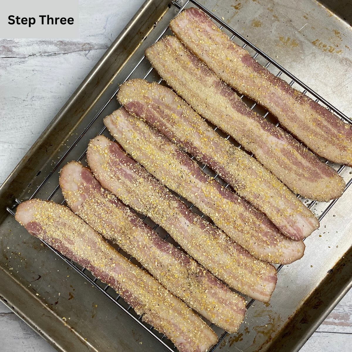 Brown sugar bacon on a rack and baking pan ready for the oven.