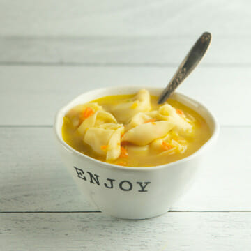 Chicken tortellini soup in a bowl with a spoon.