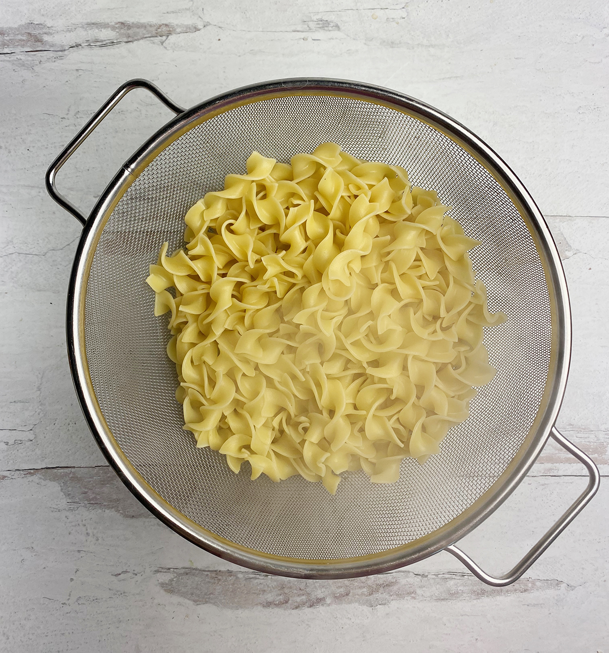 Pasta draining in a strainer.