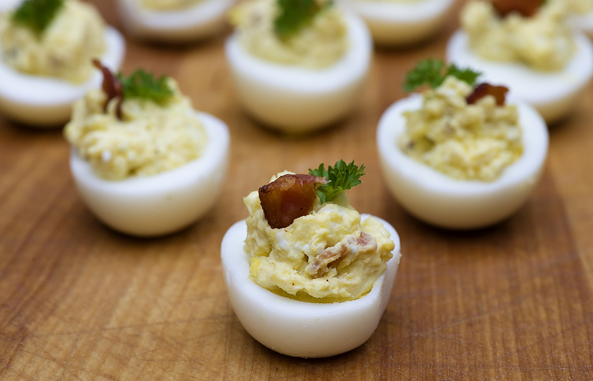 Bacon blue cheese deviled eggs on a wooden board.