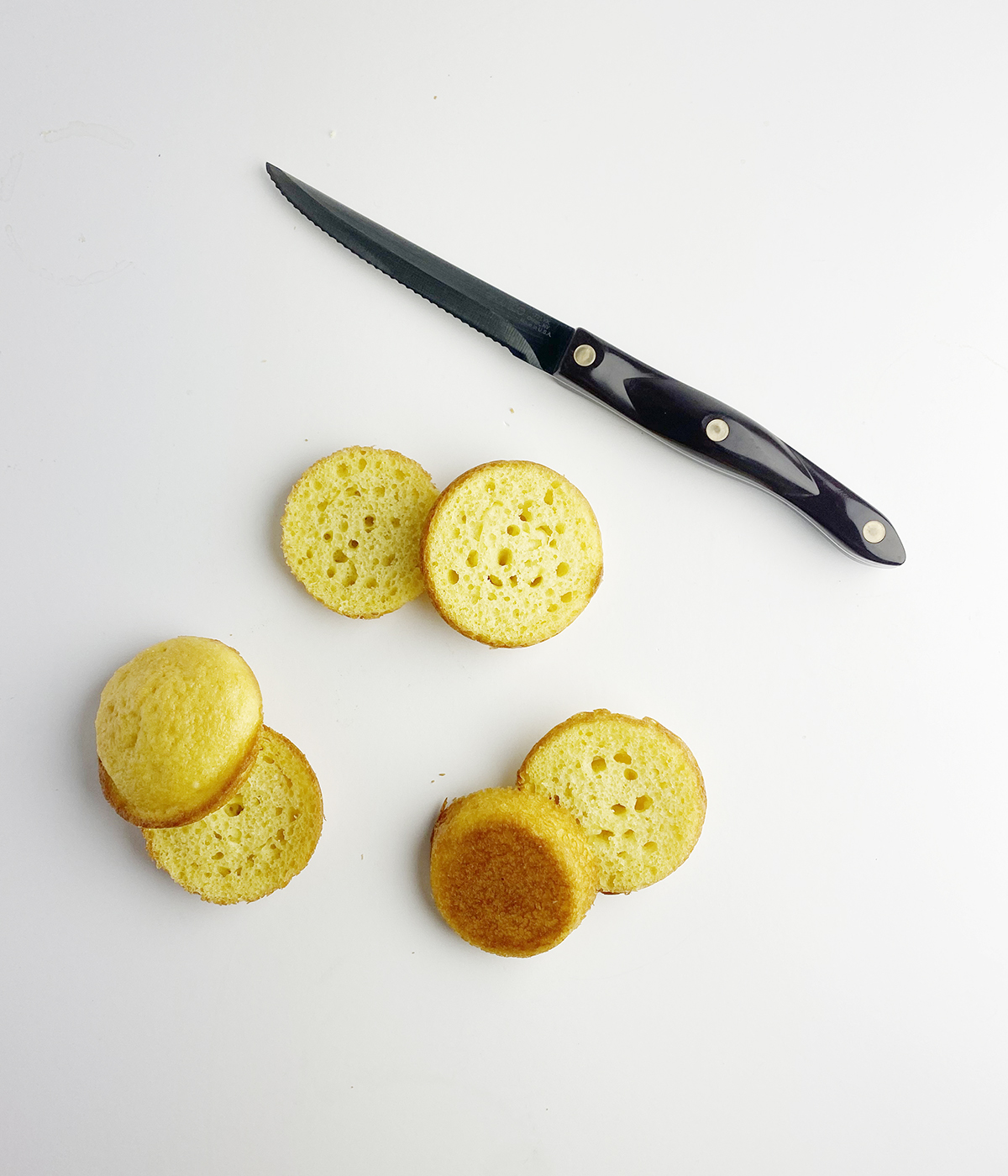 Sliced cupcakes for Boston Cream pie Cupcakes, with a knife.