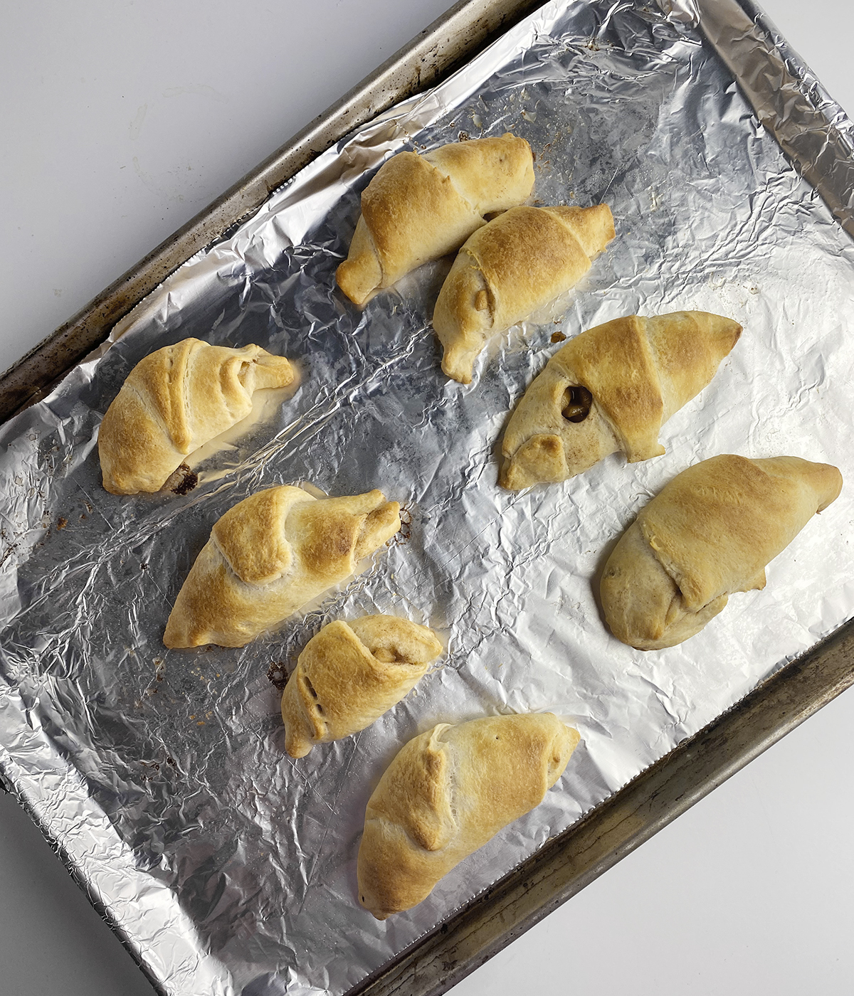 Baked mini apple pies on a foil-lined baking sheet.