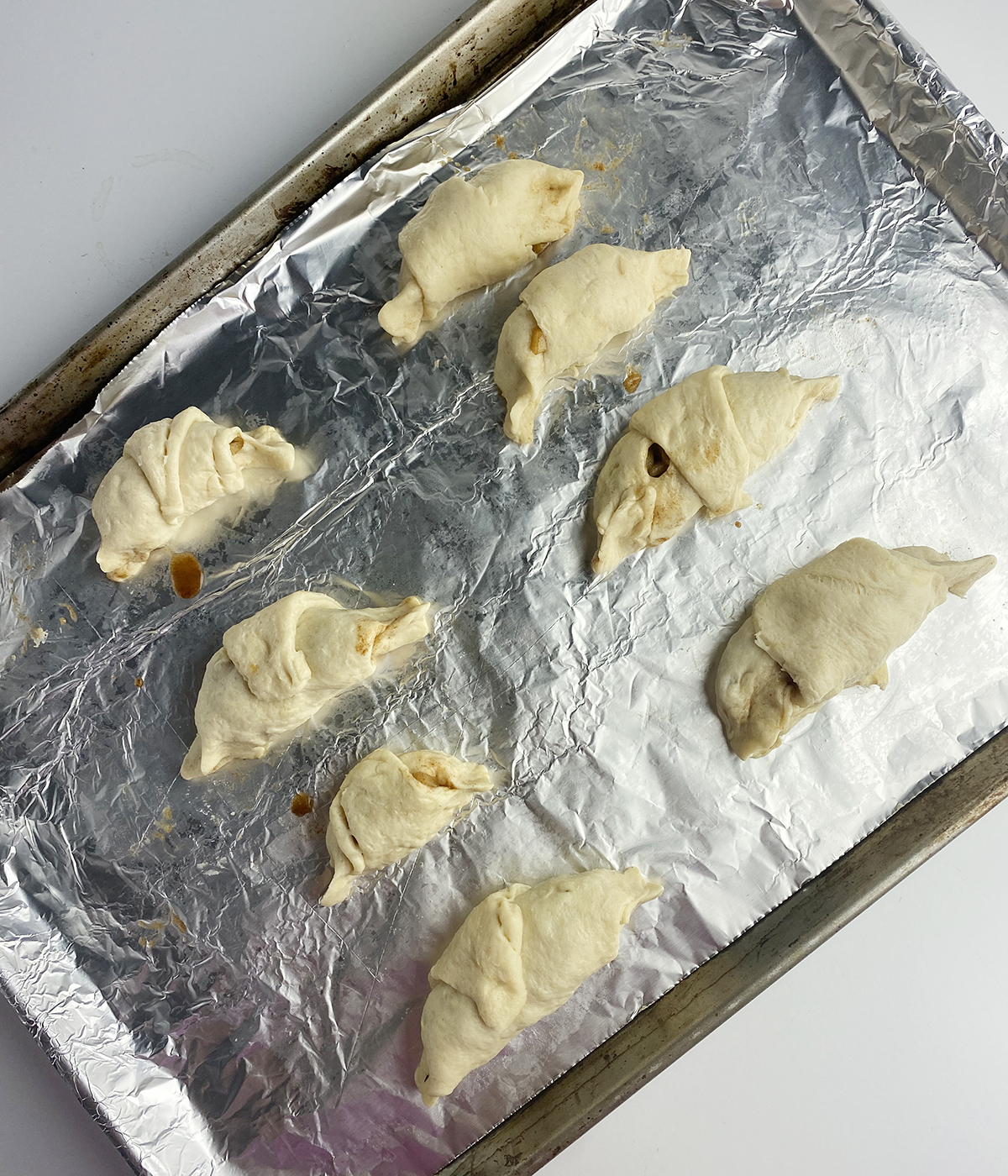 mini apple pies on a baking sheet ready for the oven.