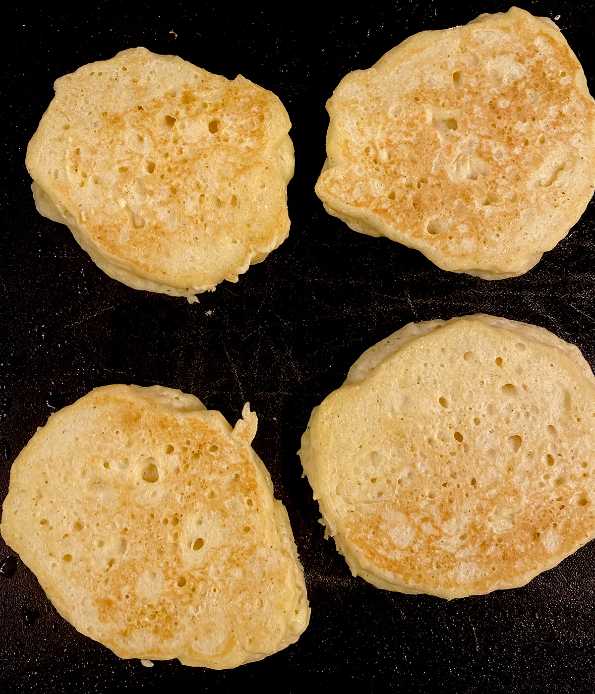 Buttermilk Cornmeal pancakes cooking on a griddle.
