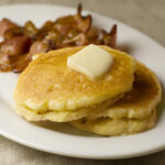 Buttermilk Cornmeal Pancakes on a plate with bacon.