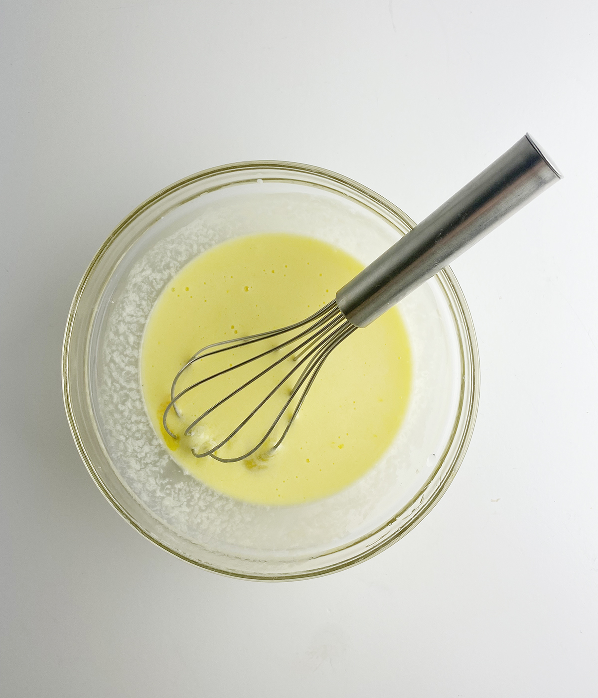 Buttermilk and egg mixture in a bowl with a whisk.