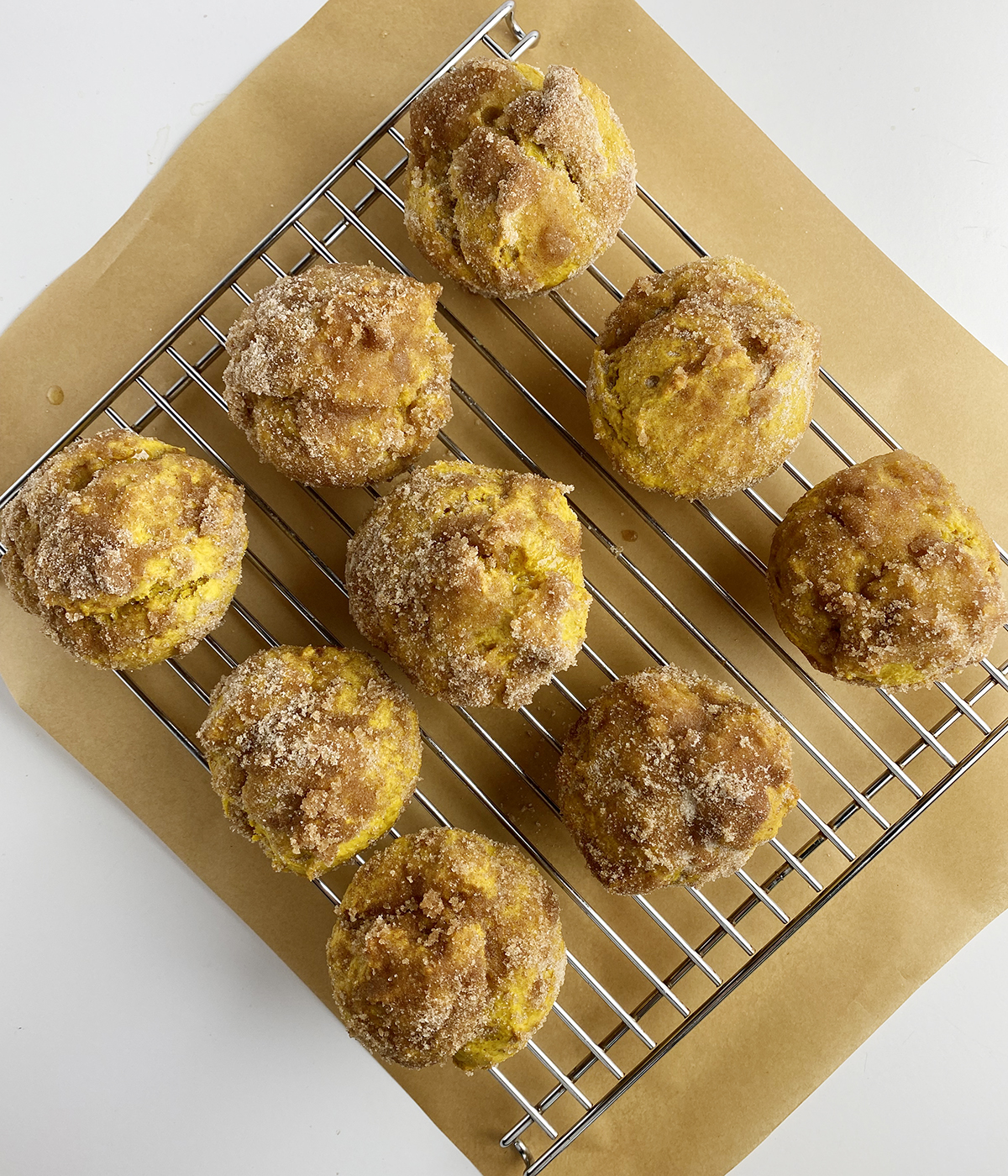 Pumpkin donut muffins cooling on rack.