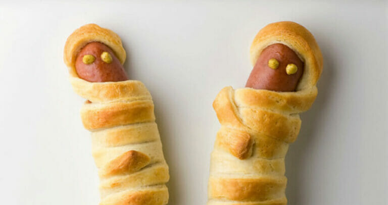 Hot dog mummies on a white plate.