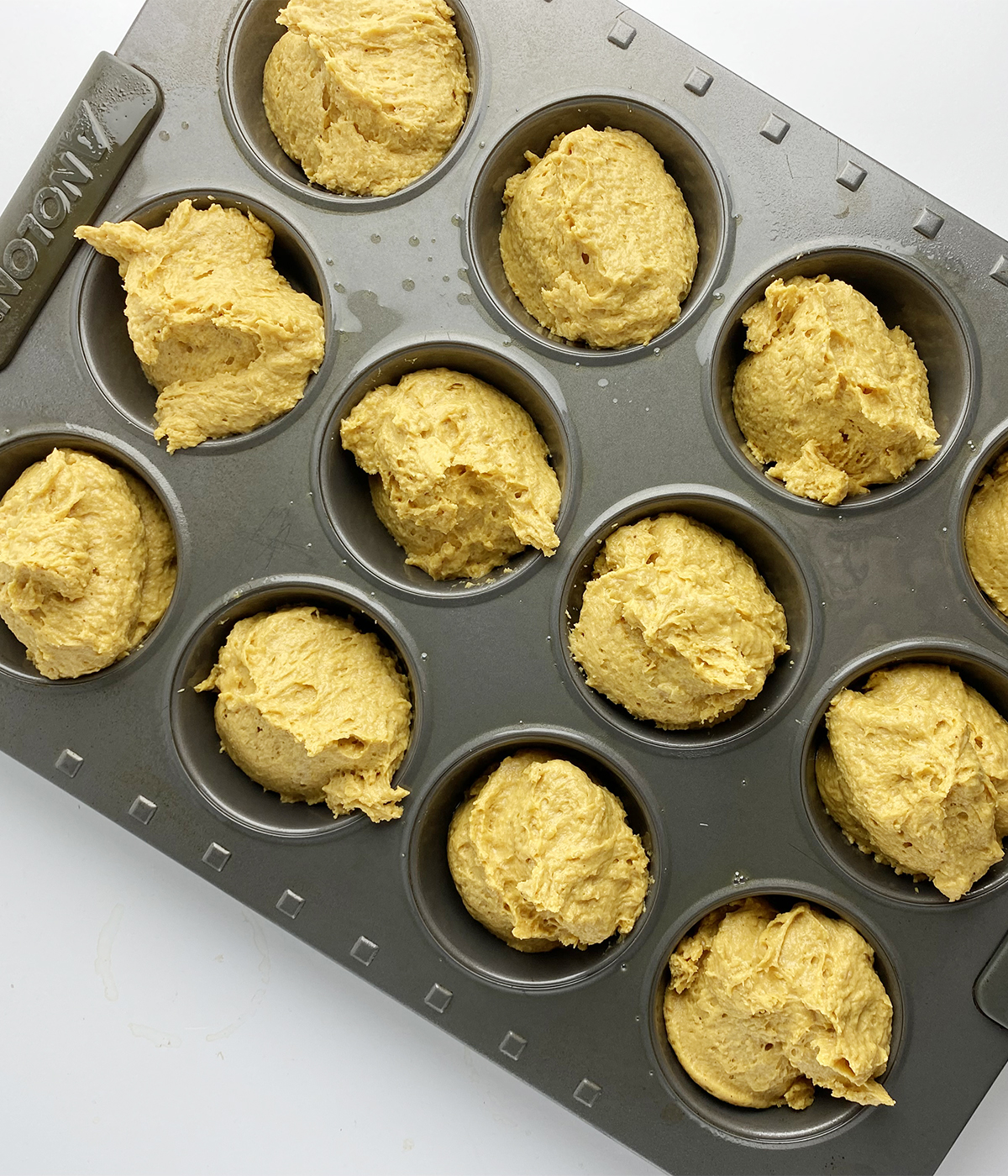 Pumpkin muffin dough in a 12 cup muffin pan.