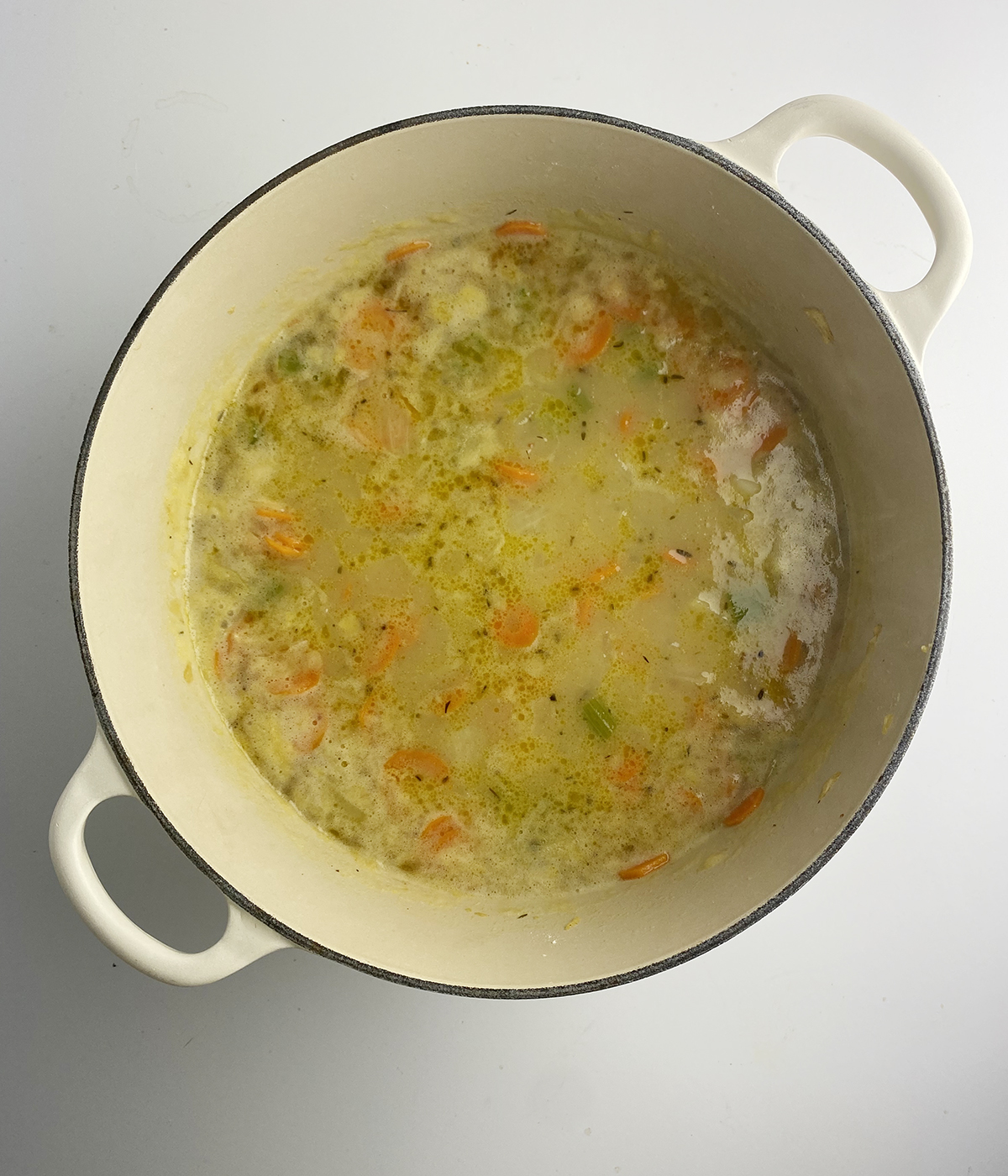 Chicken broth with vegetables in a Dutch oven.