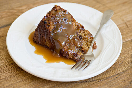 A slice of easy apple cake with caramel sauce on a plate with a fork.