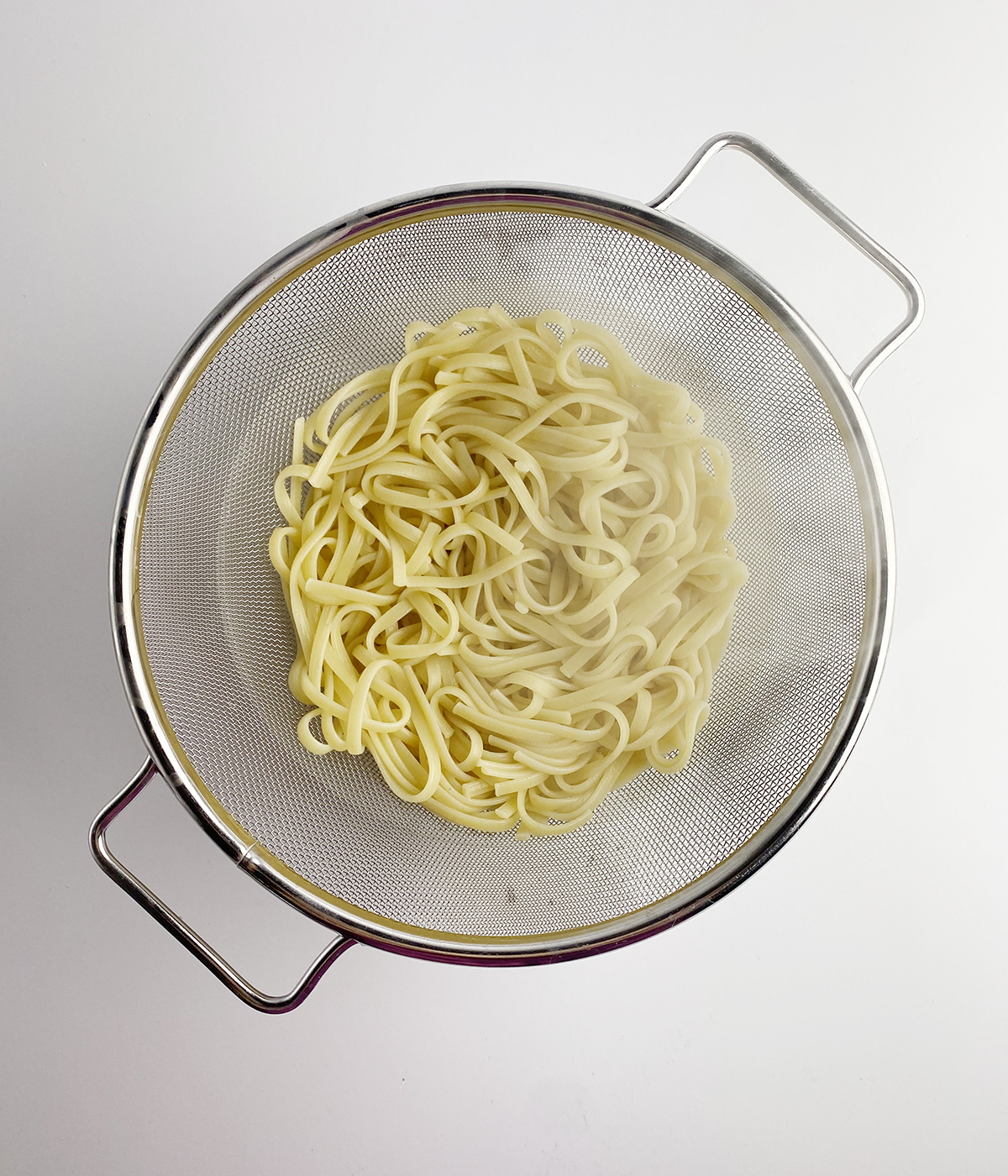 Pasta draining in a skillet.