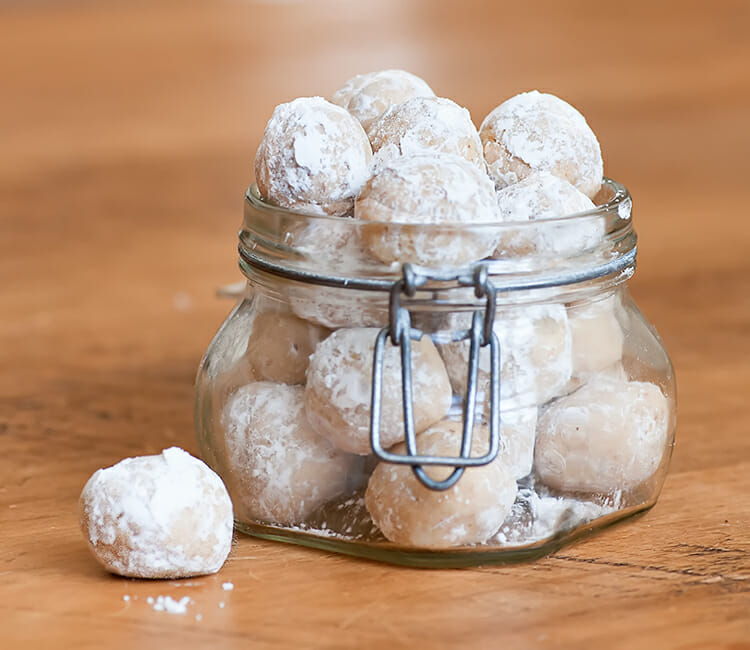 No Bake Rum Balls in a jar on a wooden surface.