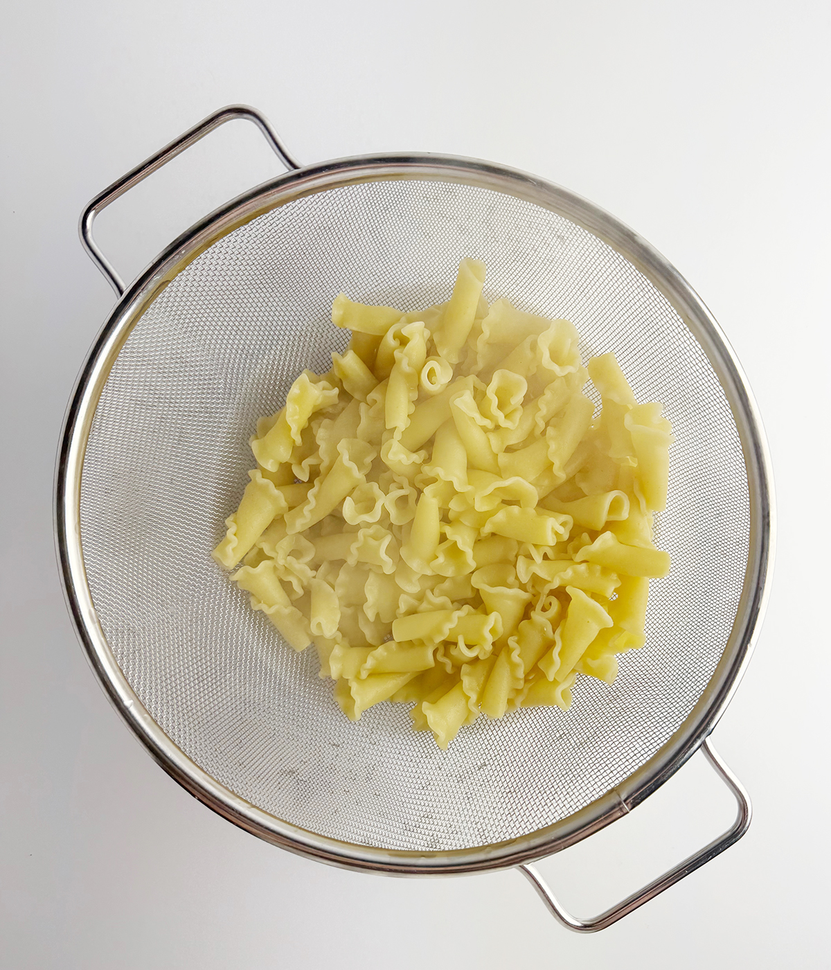 Pasta draining in a strainer.