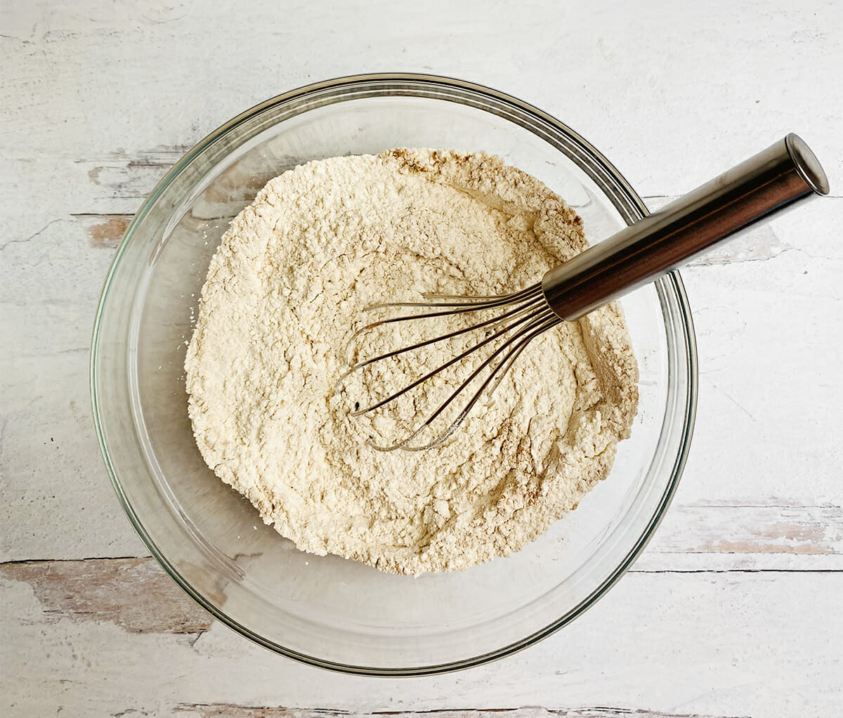 Mixed flour and cinnamon with a wisk in a mixing bowl.