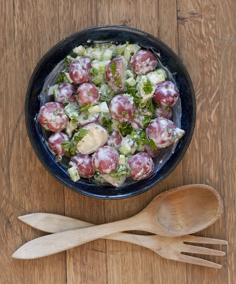 Boursin potato Salad in a bowl with salad tongs.