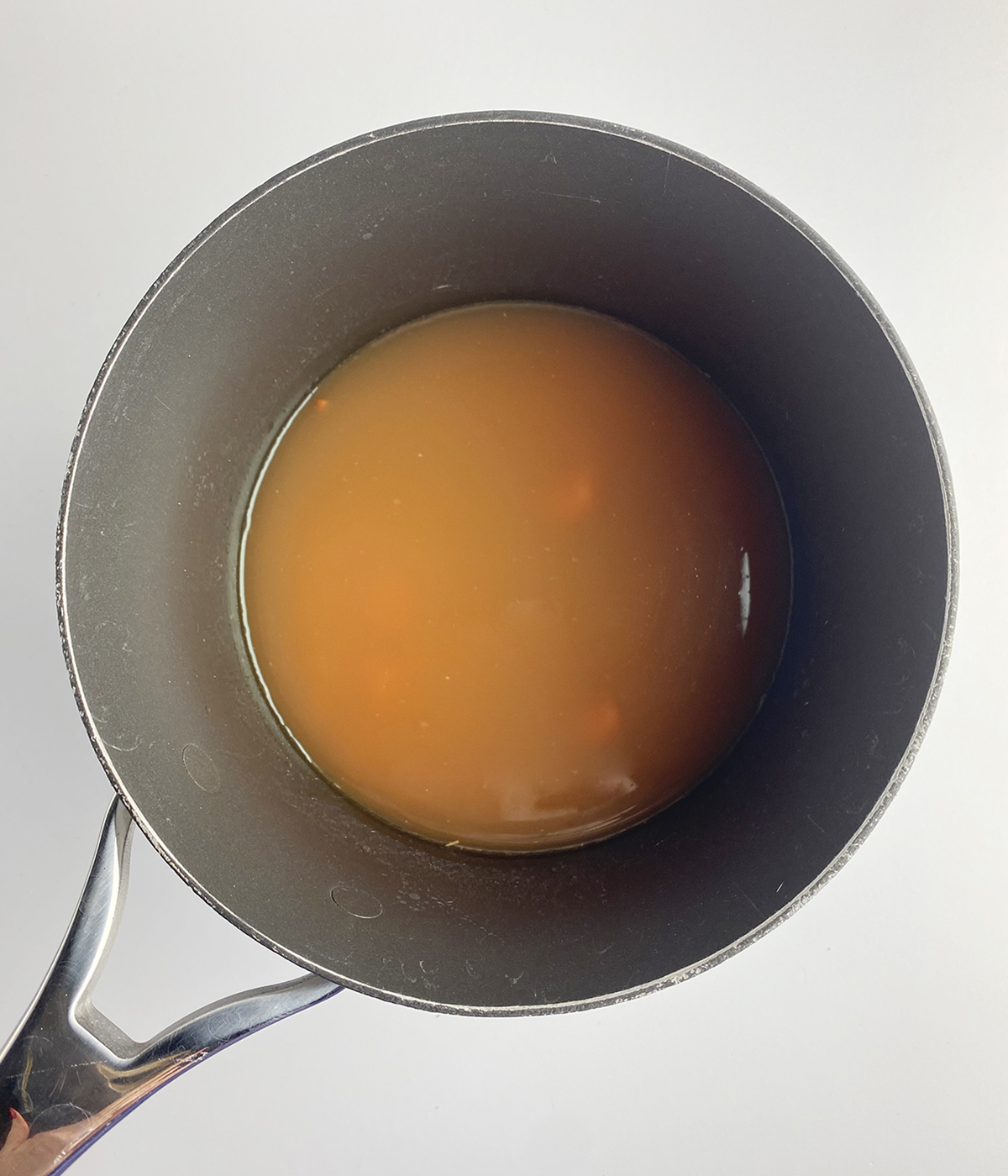 Chicken broth, carrots and pasta in a pot.