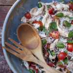 Chicken rice salad in a bowl with serving spoons.