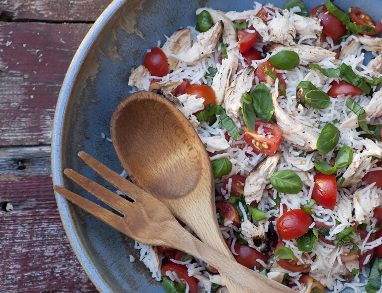Chicken rice salad in a bowl with serving spoons.