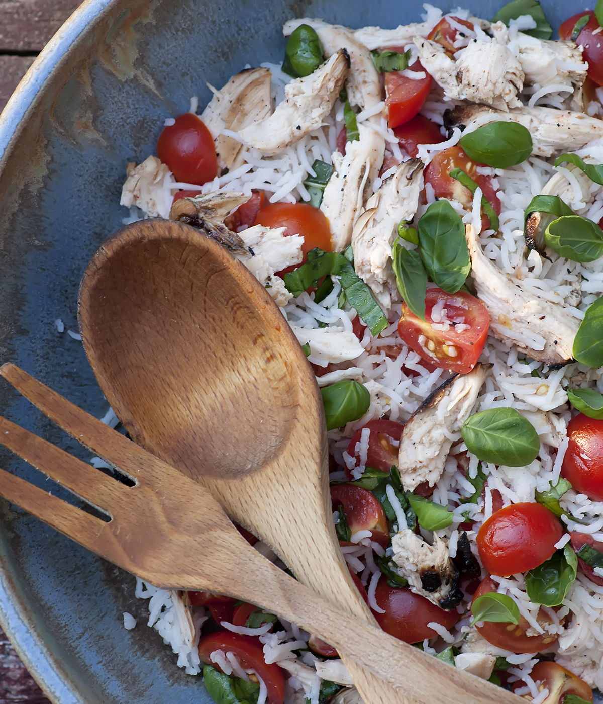Chicken rice salad in a dish with wooden servers.