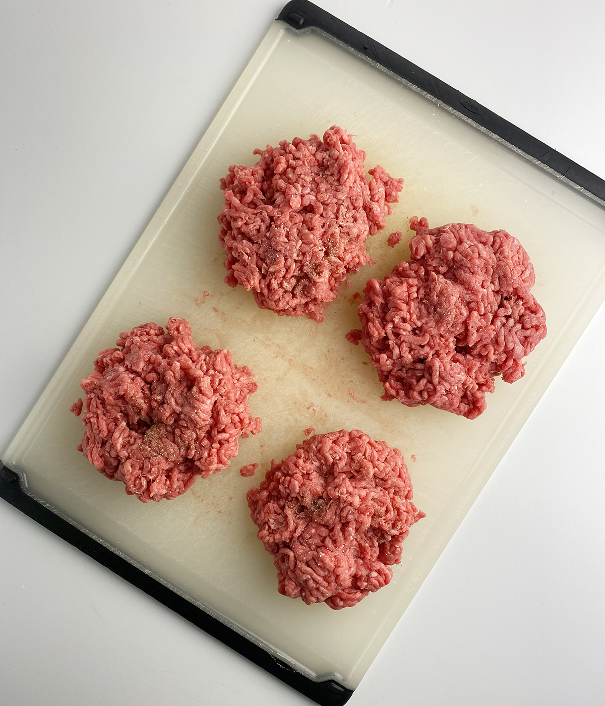 Burger patties on a cutting board.