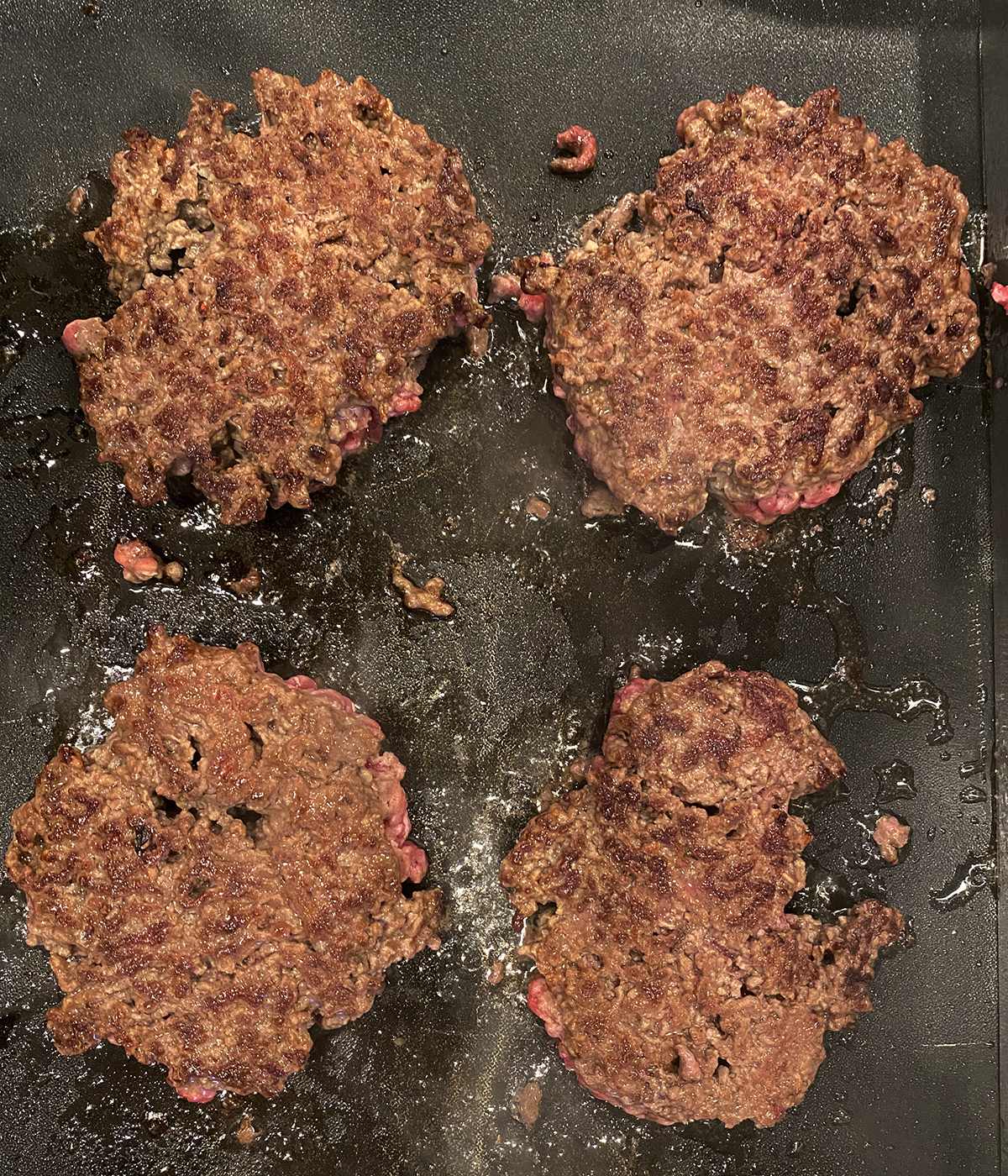 Burgers cooking on a griddle.