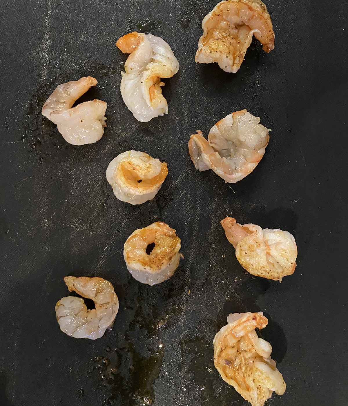 Shrimp cooking on a griddle.