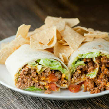 Taco wraps on a plate with tortilla chips on the side.