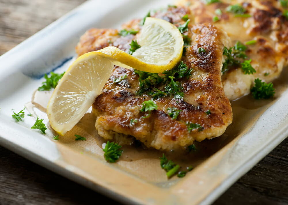 Chicken Francese on a plate with lemon.