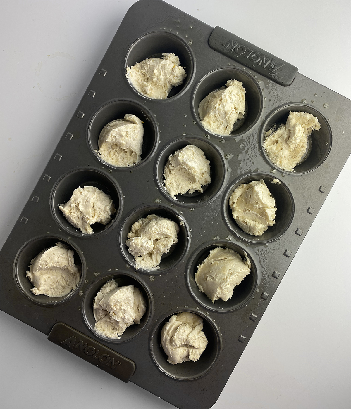 Butter biscuits batter in a muffin tin.