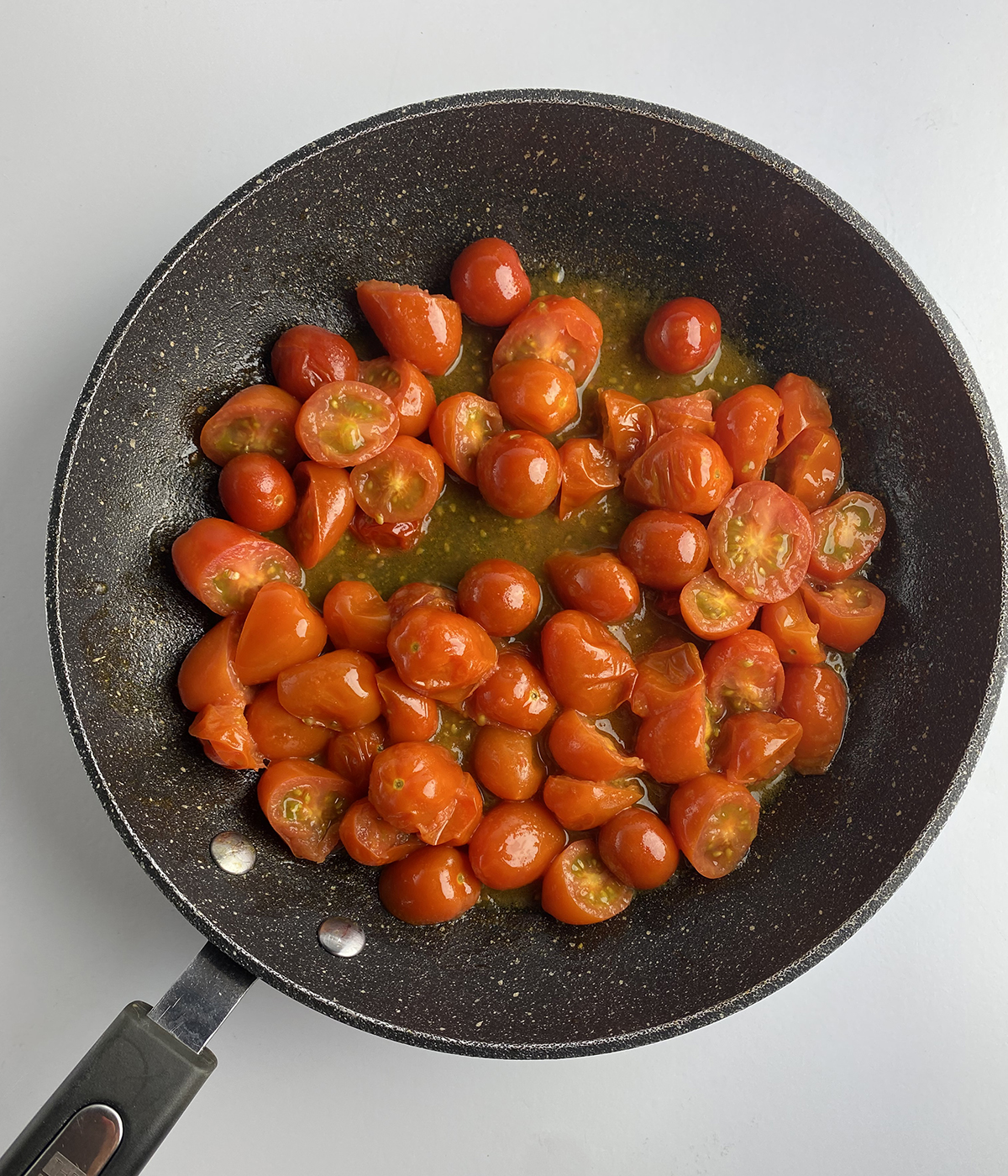 Cooked cherry tomatoes in a skillet.