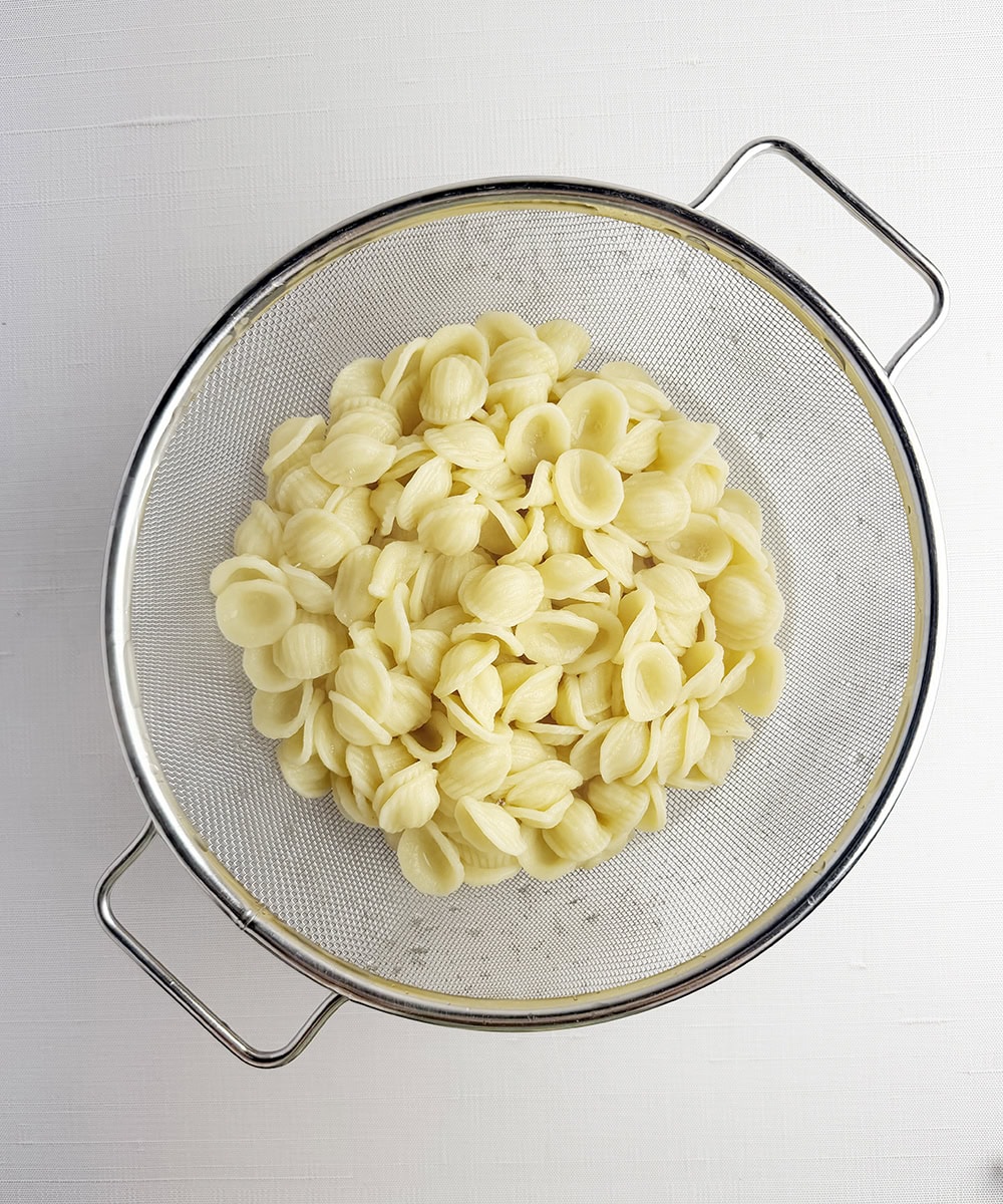 Drained orechiette pasta in a strainer.